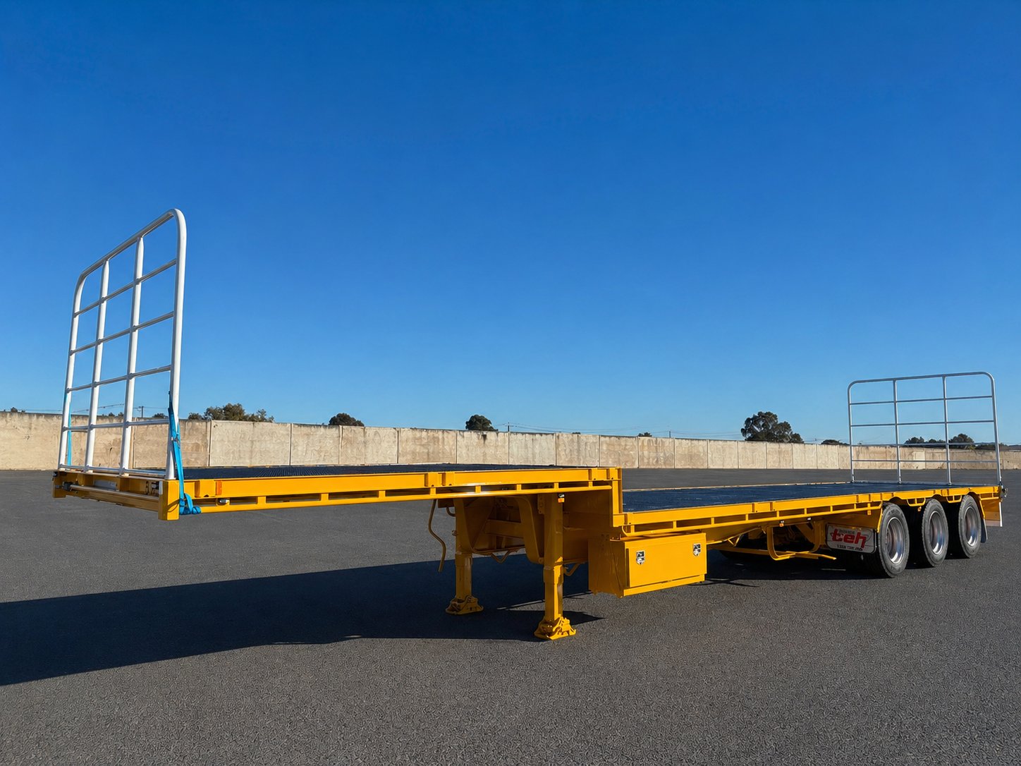 TEH drop deck trailer with load gates on the yard